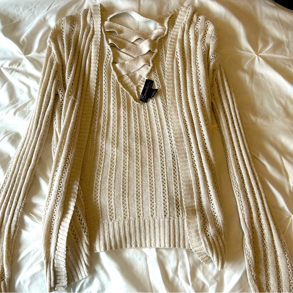 Soft creme-colored cardigan sweater with interlace on the back